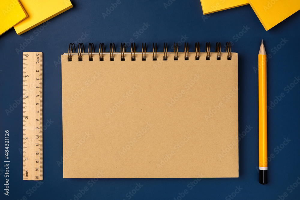 Poster top view brown notebook with yellow pencil and notepad on navy blue working table