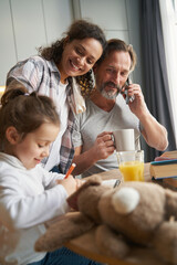 Joyful mother smiling at her daughter while she painting