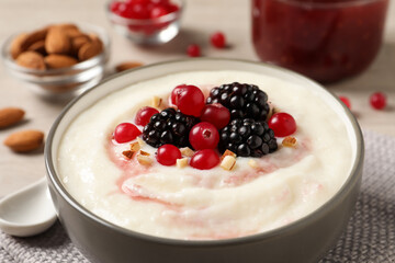 Delicious semolina pudding with berries in bowl on table, closeup