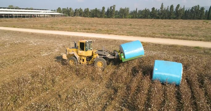 Kibbutz, Israel - 25 November 2021: Aerial view of a tractor loading cotton bales on truck, Kibbutz Saar, Mate Asher, Israel.