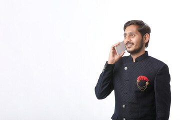 Young indian man talking on mobile phone over white background.
