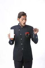 Young indian man in tradition wear and showing smartphone screen on white background.