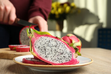 Plate with delicious cut white pitahaya fruit on wooden table indoors, closeup