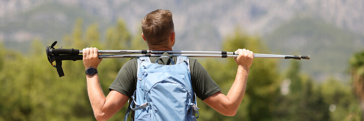 Man hiker is holding Finnish walking sticks to top of mountain
