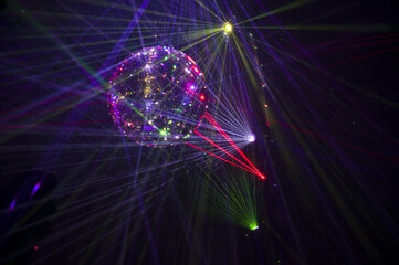 Mirrored Disco Ball and bright beams at the night party. Party attribute reflects Lazer lights. Abstract background with defocused rays. Night club atmosphere. Installation at Vilnius light festival