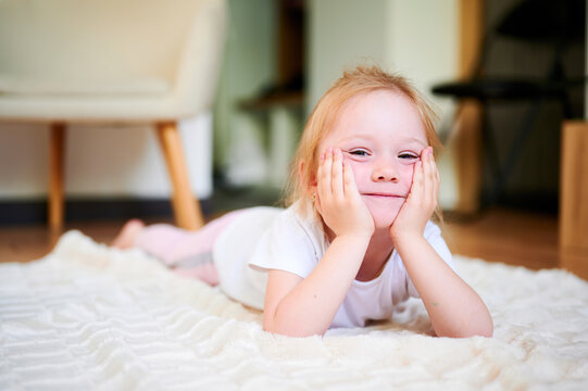 Cute little girl lying on the floor at home and smile