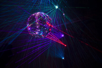 Mirrored Disco Ball and bright beams at the night party. Party attribute reflects Lazer lights. Abstract background with defocused rays. Night club atmosphere. Installation at Vilnius light festival