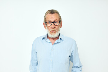 Senior grey-haired man in blue shirts gestures with his hands light background