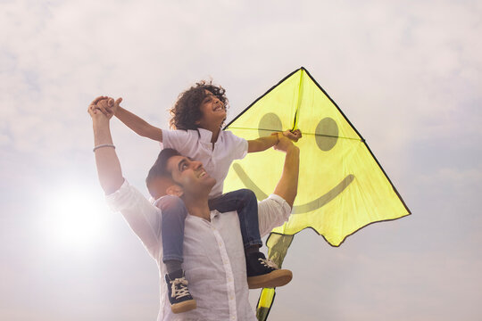 Son sitting of his father shoulder with holding a kite