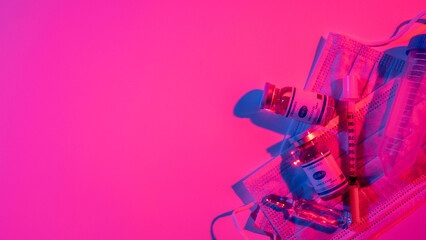 Covid-19 vaccine. Pharmaceutical banner. Laboratory research. Neon light ampoule dose syringe test tube face mask composition on bright pink color empty space background.