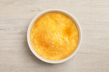 Delicious creme brulee in ceramic ramekin on white wooden table, top view