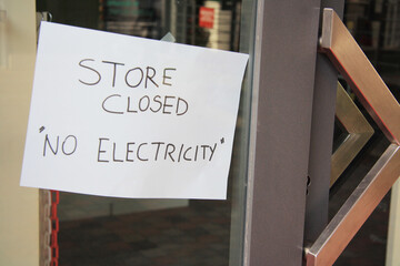 Sign posted in a shop window: Shop closed, no electricity. Energy crisis, blackouts concept.