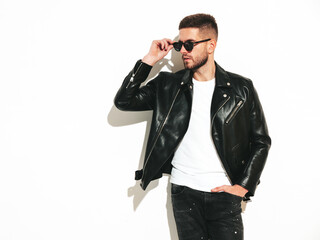 Fototapeta premium Portrait of handsome confident model. Sexy stylish man dressed in biker leather jacket and black jeans. Fashion hipster male isolated on white in studio. In sunglasses