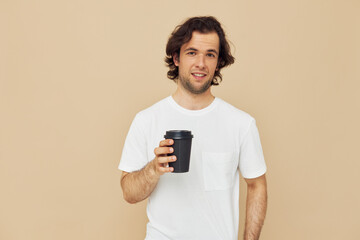 Attractive man in a white T-shirt with a black glass in hand Lifestyle unaltered