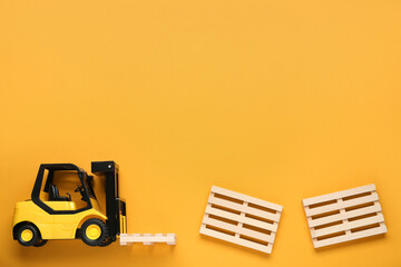 Toy forklift and wooden pallets on orange background, flat lay. Space for text