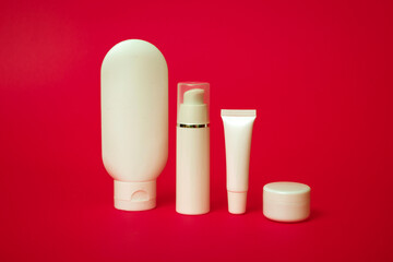Closeup of white tubes for various cosmetics on a red background. With copy space.