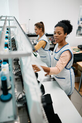 Multiracial female workers using embroidery machine while working in clothing factory.