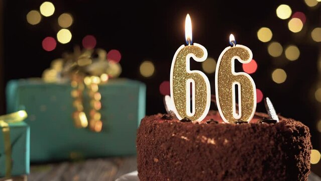 Birthday candle number sixty six on a sweet cake on the table, 66th birthday. Fire from the lighter, blow out the holiday candle.