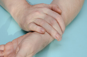 A middle-aged man with his hand on his wrist.