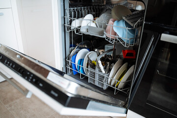 Dishwasher. Equipment for washing plates. Loading the drawer with dishes. open door of kitchen appliances.