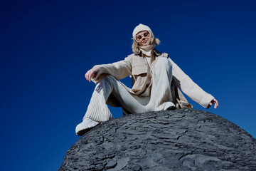 Fototapeta premium young woman sitting on a stone nature blue sky in a hat lifestyle