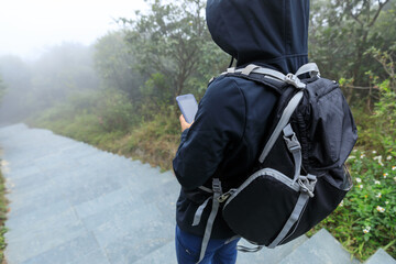 Hiker using smartphone at the foggy mountain top