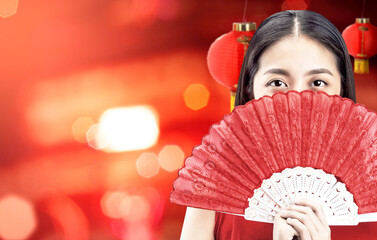 Asian Chinese woman in a cheongsam dress holding fan celebrates Chinese New Year