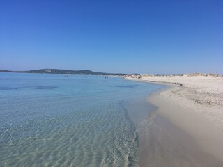 White sandy beach and sea. Blue water and blue sky. Clean water. Holiday. Sunny day. Summer. Porto Pino. Sardinia. Italy