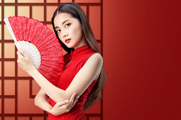 Asian Chinese woman in a cheongsam dress holding fan celebrates Chinese New Year