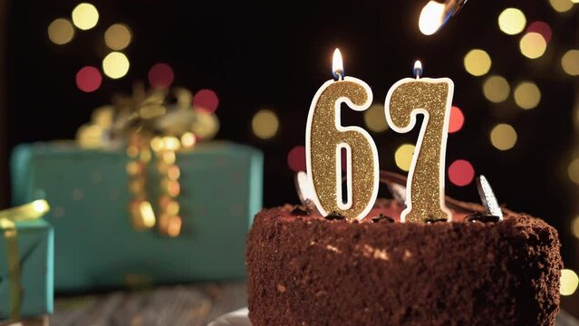 Number sixty seven birthday candle on sweet cake on the table, 67th birthday. Fire from the lighter, blow out the holiday candle.