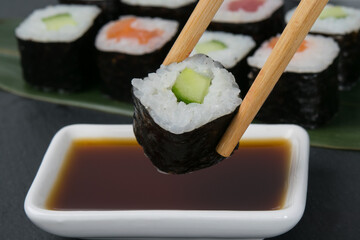 bamboo sticks dip a roll with cucumber in soy sauce