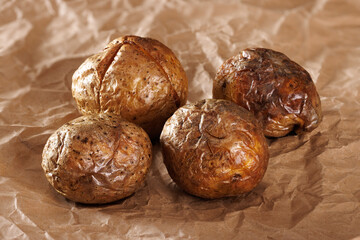 Whole baked potato tubers on brown kraft paper. Close-up.