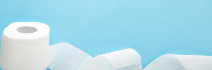 Soft, white unrolled toilet paper on light blue table background. Pastel color. Hygiene concept....
