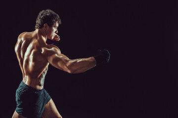 Side view of boxer in red gloves who practicing swing on black background. Sport concept 