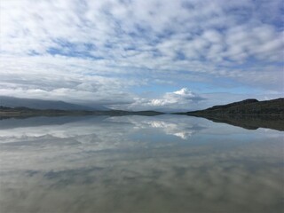 Sky reflection on a lake in a sunny day. Clouds and mountains. Mirror effect. Egilstaddir. Iceland.