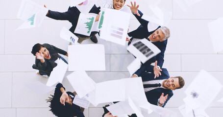 Fototapeta na wymiar Were done for the day. Aerial shot of a diverse group of businesspeople throwing paperwork in the air in celebration while in the office.