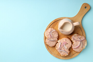 Board with pate sandwiches on blue background