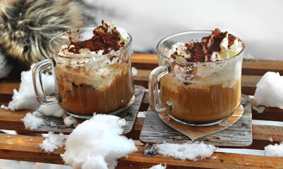 two cups of cappuccino placed on a wooden sled in the  snow