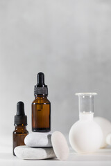 Brown droppers with cosmetics on a pedestal of stones and vacuum cupping massagers in the background.