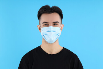 Young man in medical mask on blue background