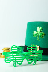 Top hat, chocolate coins and clover leaf glasses on white table
