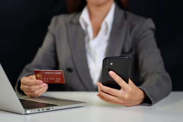 Woman hands sitting and holding credit card and using smart mobile phone and laptop computer on table for online payment or shopping online. Businesswoman using internet for working. E-Banking concept