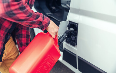 Unrecognizable man refueling his camper van with a jerrycan - obrazy, fototapety, plakaty