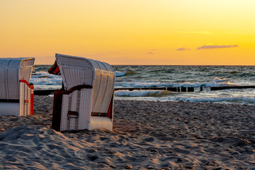 Beach chairs stand in the sunset on a beach on the Baltic Sea with sea