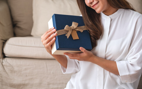 Closeup image of a young woman holding and looking at a present box