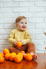 Little boy 2 years old eats tangerines. The kid wants to sit on citrus fruits for the first time. Healthy fruits for children