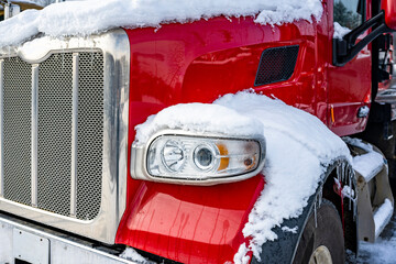 Shiny red big rig semi truck tractor standing for truck driver rest on the winter truck stop...