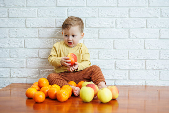 Cute smiling kid eating one fresh juicy red apple. Healthy fruits for young children