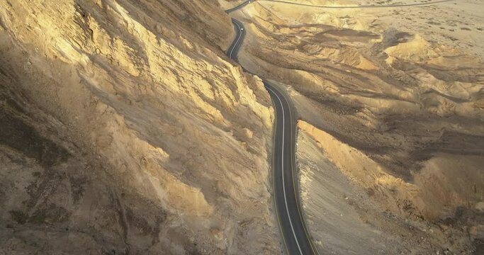 Aerial view of a winding road on a mountain side in the desert at sunrise, Paran rive, Negev, Israel.