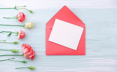 Blank card in pink envelope with flowers on mint background.